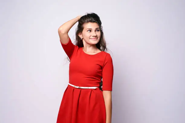 Portrait girl. Beautiful brunette. Red dress. White background.