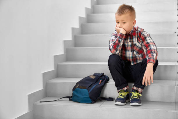 istock Lonely schoolboy sitting on stairwell in school, thinking. 1150675628
