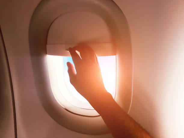 istock Passenger's hand closing the window shade on a modern airplane. 1150676101