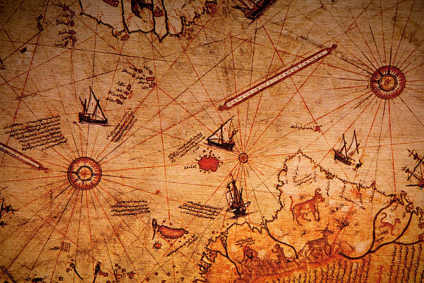 Close-up of globe showing a map of the American continent and atlantic ocean and ship steering wheel model for world travel concept and shipping maritime business on blurred table background.