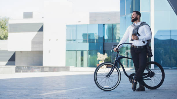 istock Young businessman holding cup of coffee while leaning at his bicycle 1150685607