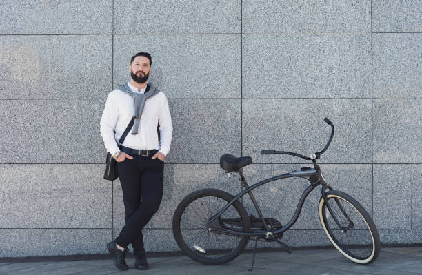 istock Businessman standing against building wall with his bicycle. 1150685632