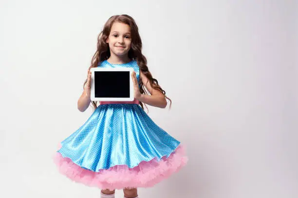 Modern technologies. Beautiful little girl. Lush blue dress.