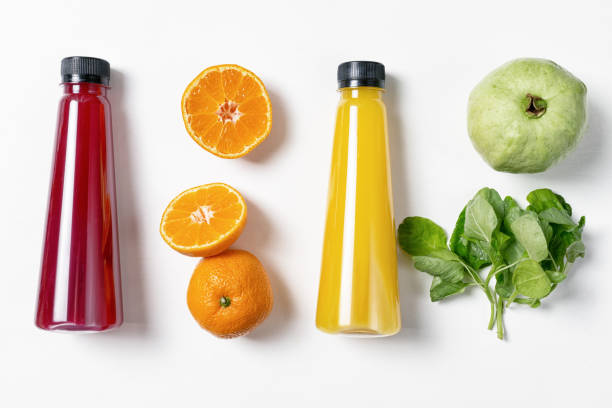 Fresh fruits in raws with juice bottles on white background. Red, orange, yellow and green. Food ingredients, detox stock photo