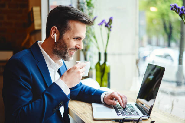 istock Businessman having videocall on laptop while drinking coffee in cafe 1150690062