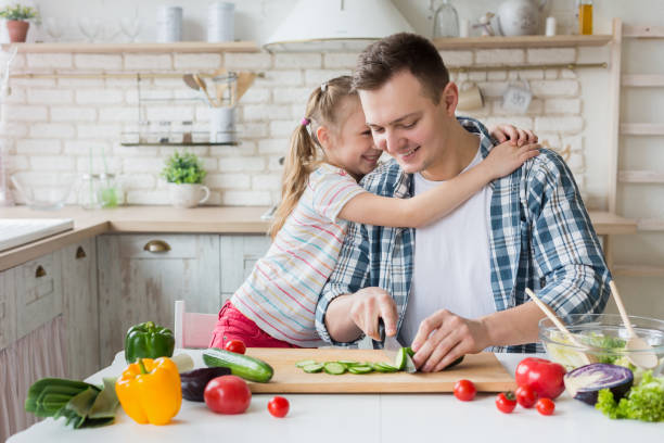 istock Pretty girl hugging dad while man cooking healthy dinner 1150690762