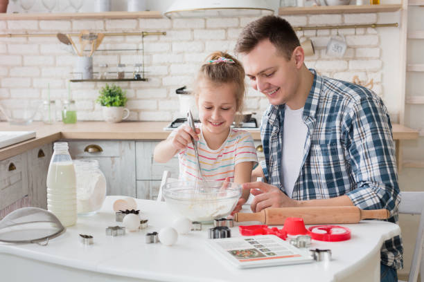 istock Dad and daughter mixing dough in bowl, preparing cake 1150690778