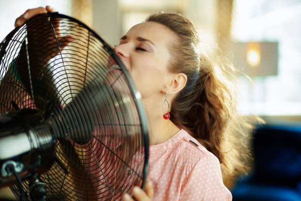 istock elegant woman cooling down using electric floor standing fan 1150694559