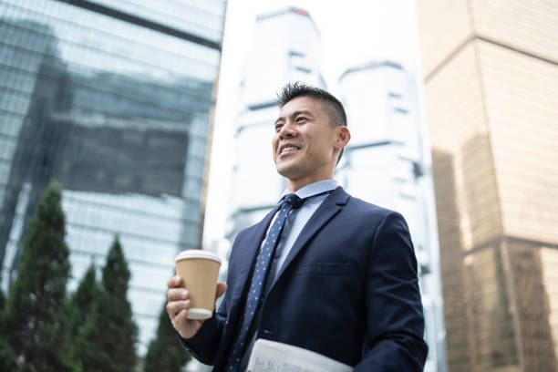 istock Businessman holding coffee cup and documents on street 1150696402