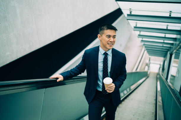 istock Businessman holding coffee cup and moving up on escalator 1150696414