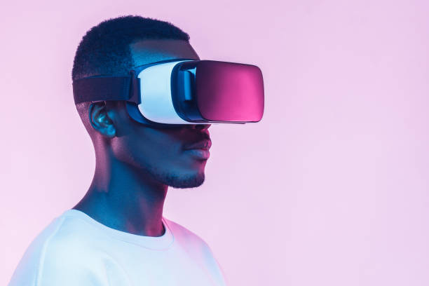 istock VR concept. Young african man wearing  virtual reality goggles, isolated on pink background 1150698639