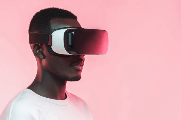 istock VR technology. Young african man wearing virtual reality headset, isolated on pink background 1150698651