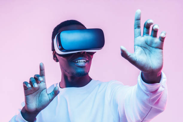 istock Young african man wearing  virtual reality goggles with hands up, isolated on pink background 1150698652