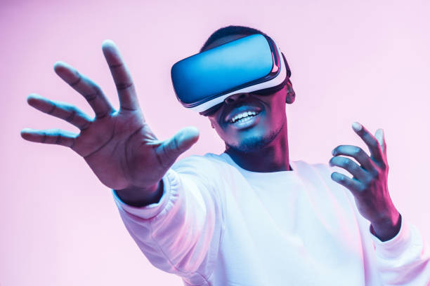 african american man in vr glasses, playing video games with virtual reality headset, trying to touch something with hand - capacete imagens e fotografias de stock