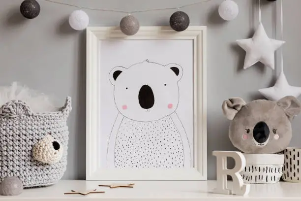 Photo of The modern scandinavian newborn baby room with mock up poster frame, koala bear, cotton basket with children accessories. Cozy interior with gray walls. Haniging cotton balls and stars. Template.