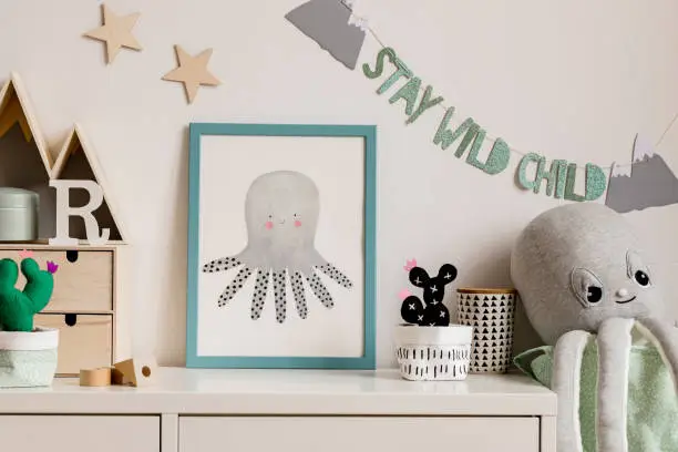 Photo of Cozy scandinavian nursery interior with mock up photo frame, plush octopus, cacti and wooden accessories. Hanging stylish inscription and stars on the white background wall. Template. Real photo.