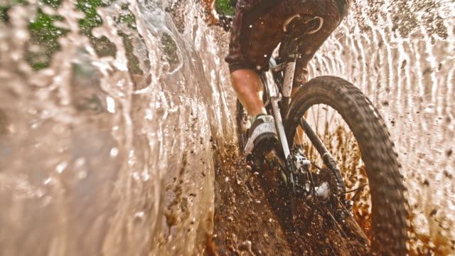 SLO MO TS Mountain biker riding through large muddy puddle