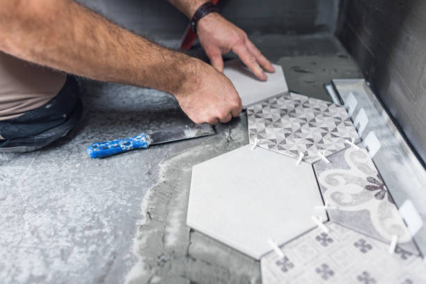 Anonymous image of adult tile mason laying ceramic tiles on the bathroom floor