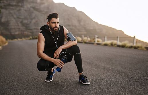 Shot of a sporty young man drinking water while exercising outdoors