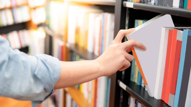 istock Male hand choosing white book from bookshelf 1150704223