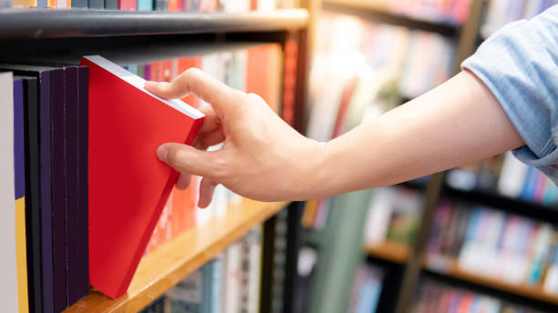 istock Male hand choosing red book from bookshelf 1150704240