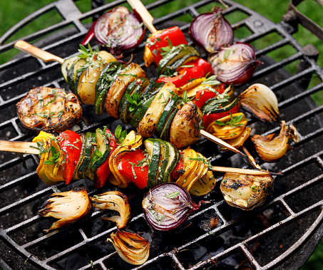 Vegetarian skewers, grilled vegetable skewers of zucchini, peppers and potatoes with the addition of aromatic herbs and olive oil on the grill outdoors. Grilled food