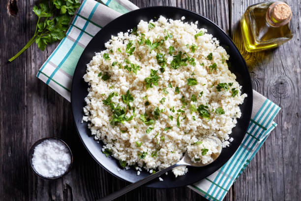 Cauliflower rice or couscous mixed with finely chopped parsley overhead view of Cauliflower rice or couscous mixed with finely chopped parsley in a black bowl on an old rustic table, horizontal view from above, close-up, macro finely stock pictures, royalty-free photos & images