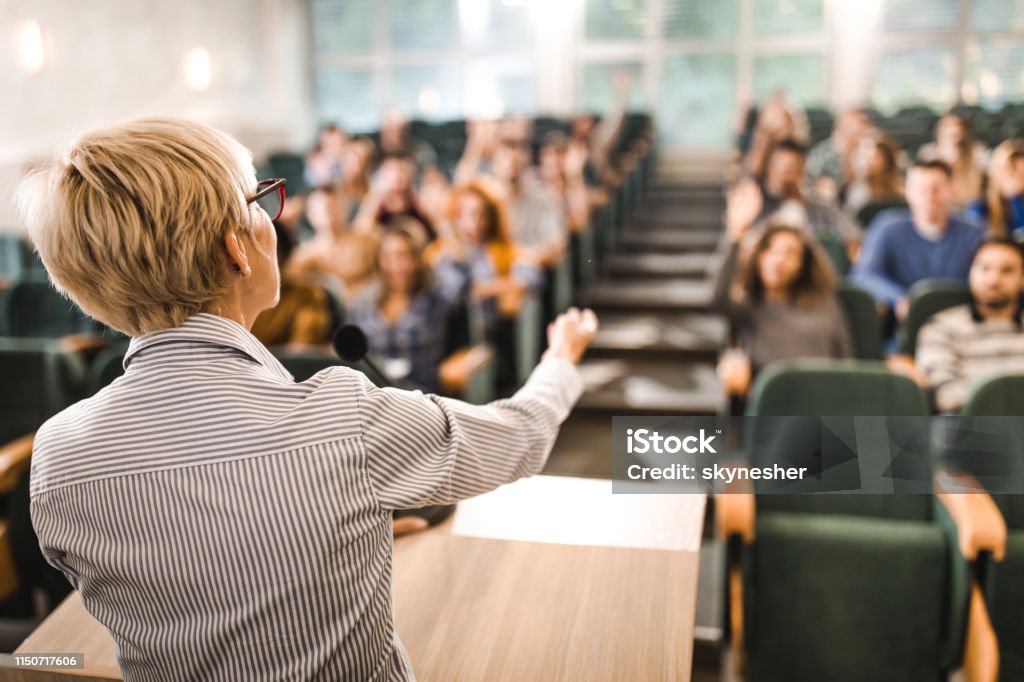 Rückansicht eines reifen Lehrers, der einen Vortrag in einem Klassenzimmer hält. - Lizenzfrei Hörsaal Stock-Foto