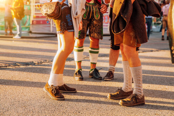 Eine Gruppe von Menschen beim Bierfestival in München, Deutschland. Die Frau trägt typisches Dirndl und die Männer Lederhosen - die traditionelle bayerische Kleidung.