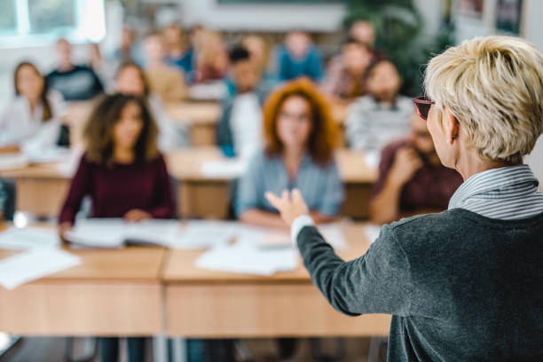 istock Back view of a senior professor talking on a class to large group of students. 1150718996