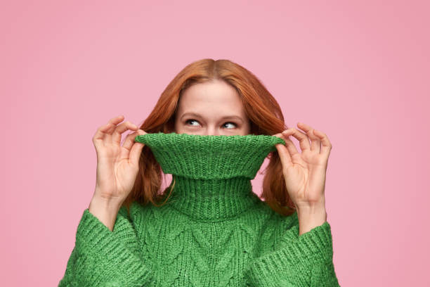 istock Playful girl covering face with sweater roll neck 1150723049