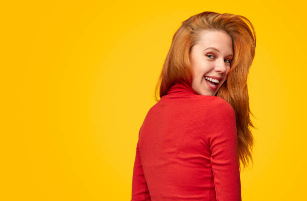 istock Smiling redhead woman on orange backdrop 1150723091