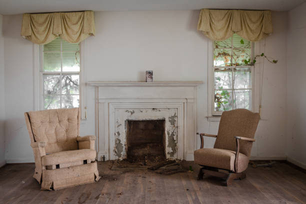 sala de estar con dos sillas con chimenea en una casa abandonada - slum living fotos fotografías e imágenes de stock