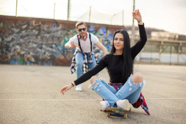 young couple having fun with a skateboard - pair couple mid adult happiness imagens e fotografias de stock