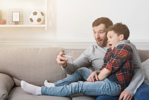 istock Funny father and his son taking selfie at home 1150725557