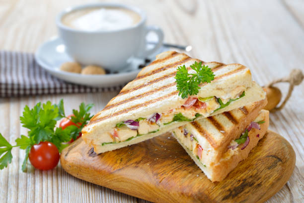 Grilled sandwich with a cappuccino Pressed panini with grilled chicken breast fillet, tomatoes, onions and lettuce, served with a cappuccino panino stock pictures, royalty-free photos & images