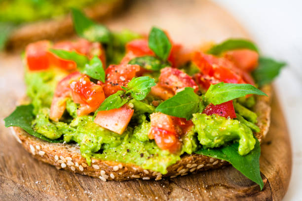 Avocado Sandwich Garnished with Tomato and Basil Macro shot of super delicious and ready to eat slice of sandwich with super healthy ingredients like avocado, tomato and basil. kruis stock pictures, royalty-free photos & images