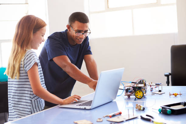 放課後のコンピュータコーディングクラスの教師の組み立てのロボット車を持つ女子学生 - african ethnicity student child group of people ストックフォトと画像