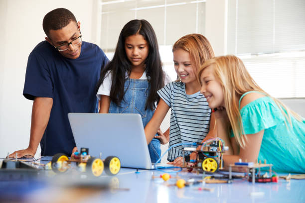 istock Three Female Students With Teacher Building Robot Vehicle In After School Computer Coding Class 1150731198