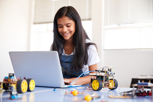 Mujer estudiante edificio y Programing vehículo robot en después de la escuela de codificación de computadora clase photo
