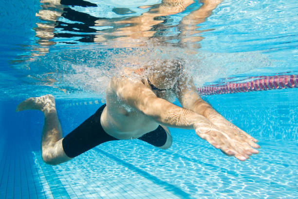 junge männliche athletin schwimmt brustschwimmen unter wasserblick - breaststroke stock-fotos und bilder