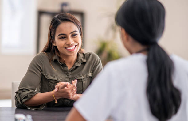 Speaking To The doctor A stressed-out woman is chatting with her mental health counselor. She is explaining her problems. She is staying positive with a smile. counseling stock pictures, royalty-free photos & images