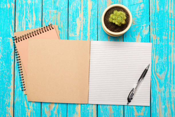 istock Top view workspace with blank notebook and pen on wooden table background 1150732928