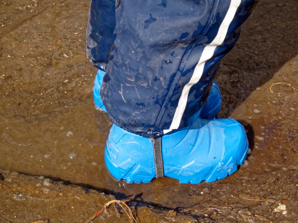 istock the child walks through puddles in rubber boots in the spring 1150732951