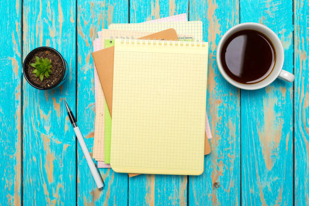istock Cup of coffee with notebook on wooden desk 1150734953
