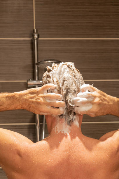 istock Back man foaming his shampoo while washing his hair in the shower 1150738414