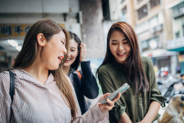 istock Modern girlfriends using smart phone all together on the street 1150739459