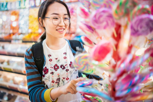 Asian girl choosing lollipops in a candy store