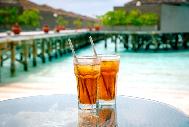 thé glacé contre tropical overwater bungalow resort sur la plage. maldives. - tea island photos et images de collection