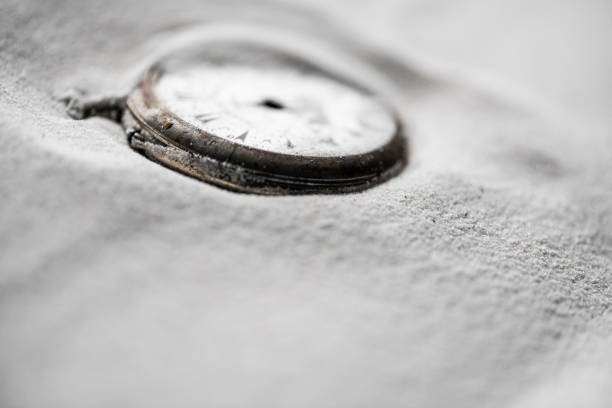 An antique pocket watch leans against an old book with yellowed pages